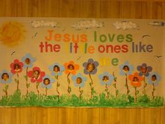 a bulletin board with flowers and jesus loves the little ones like me written on it