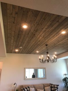 a living room filled with furniture and a chandelier hanging from the wooden ceiling