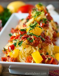 a white plate topped with pasta covered in cheese and tomato sauce next to other vegetables