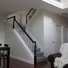 a living room filled with furniture and a stair case next to a dining table on top of a hard wood floor