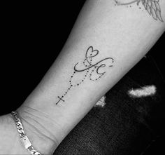 a woman's arm with a cross and wings tattoo on the left side of her arm