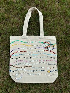 a tote bag with beads on it sitting in the grass next to some green grass