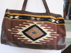 Beautiful Artison Handwoven wool (90% wool, 10% polyester to hold shape) Weekender bag with faux leather straps, bottom and sides  in Southwestern brown and multi-color designs. Note:  this is not real leather but the quality and suppleness is top quality and looks and feels like leather Bag is 18 inches wide, 11 inches high and 5 inches deep.  The handles have a 11 inch drop. There is the same leather on the sides.  Bag is lined in polyester and has one pocket.  Bag has Brown Leather Trim Tote Weekender Bag, Brown Rectangular Weekender Bag With Leather Trim, Brown Southwestern Rectangular Shoulder Bag, Southwestern Style Brown Rectangular Shoulder Bag, Southwestern Brown Rectangular Shoulder Bag, Brown Southwestern Style Shoulder Bag For Everyday Use, Bohemian Brown Weekender Bag With Leather Handles, Artisan Brown Bag For Fall, Artisan Brown Satchel With Leather Handles