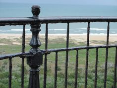 an iron fence overlooking the beach and ocean