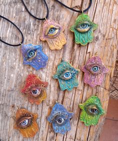 six different colored evil eye pendants on a piece of wood