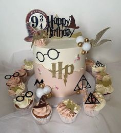 a harry potter themed birthday cake surrounded by cupcakes and other decorations on a white tablecloth