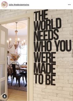 an open door leading to a dining room with a brick wall and chandelier