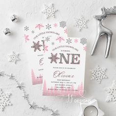 two pink and silver snowflakes are on the table next to some christmas decorations