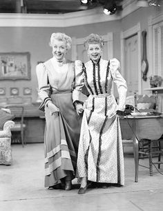 black and white photograph of two women standing next to each other in an old fashioned living room