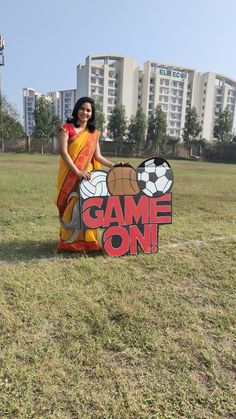 a woman standing next to a sign that says game on with a basketball and soccer ball