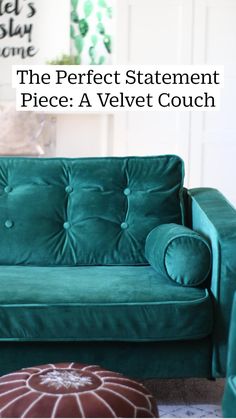 a green velvet couch sitting on top of a rug next to a footstool