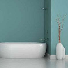 a white bath tub sitting next to a tall vase on the floor in a bathroom