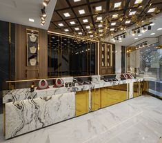 a marble counter with gold and red accents in a large room filled with mirrors, lights, and chandeliers