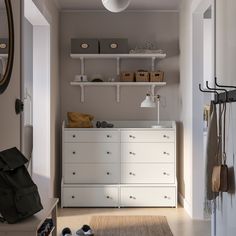 a white dresser sitting in a room next to a wall mounted mirror and coat rack