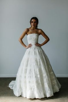 a woman in a white wedding dress posing for the camera with her hands on her hips