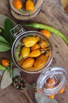 a jar filled with peppers sitting on top of a wooden table