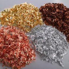 four different colors of crushed paper on a white tablecloth with silver, gold, and red foil