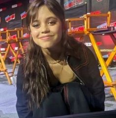 a young woman sitting in front of a red and black chair at a race track