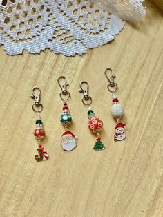 six christmas themed keychains sitting on top of a wooden table next to a lace doily