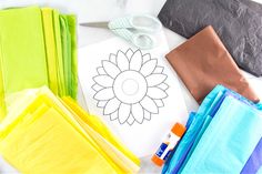 paper, scissors and other crafting supplies laid out on a white table with a flower drawn on it