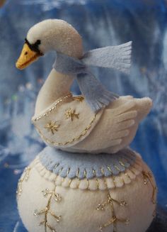 a white swan sitting on top of a ball with gold sequins around it