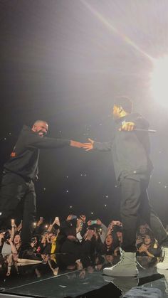 two men standing on top of a stage holding hands