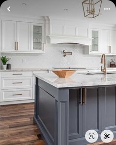 a kitchen with white cabinets and an island in the middle, surrounded by wood floors