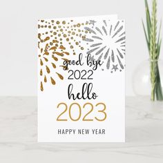 a new year card with gold and silver glitters on it, next to a potted plant