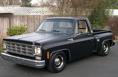 an old black pickup truck parked in a driveway