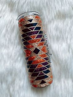 an orange and purple glitter tumbler sitting on top of a white fur covered surface