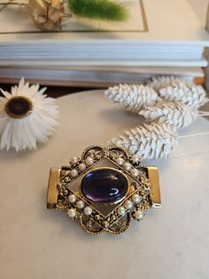 This is a beautiful medieval-style golden brooch from the 1980s inspired by medieval jewelry. It has a beautiful gold tone, although it doesn't have any markings for gold plating. It's decorated with a large violet glass cabochon and small seed pearls.   It would make a great addition to any jewelry collection and it's the perfect gift idea for a vintage enthusiast. The brooch comes with the original pin and opens perfectly. Condition: Beautiful vintage condition, with some of dark spots on the Medieval Style, Medieval Jewelry, Medieval Fashion, Seed Pearl, The 1980s, Christmas Present, Gold Tone Metal, Brooch Pin, Switzerland