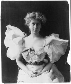 an old black and white photo of a woman wearing a dress with ruffles