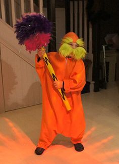 a person dressed in an orange costume holding a purple and yellow object while standing next to stairs