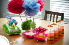 the table is set up with food and drink for an outdoor birthday party or baby shower