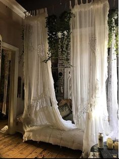 a canopy bed with sheer curtains hanging from it's sides