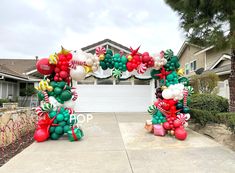 an arch made out of balloons and candy canes in front of a house with a garage