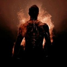 a man standing in the dark with his back turned to the camera and flames behind him