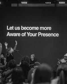 a group of people standing on stage in front of a large screen with words that read let us become more aware of your presence