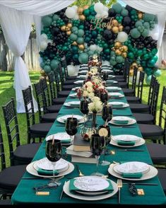 a long table is set with black, white and green decorations for an outdoor party