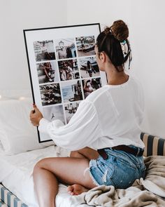 a woman sitting on top of a bed next to a framed photo with pictures behind her