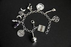 "A collection of silver plated Wicca themed charms have been dispersed around a shimmering silver plated bracelet chain in this handmade charm bracelet. This Wiccan charm bracelet is then completed with a lobster clasp and a 1/2 inch of chain at the end for adjustable sizing. Charms in this bracelet include a genuine amethyst wand charm, cauldron charm, goblet charm with athame charm, goddess charm, four corners charm, cat charm, pentagram charm, triple moon charm, and a \"wicca\" word tab charm Silver Symbolic Bracelets With Dangling Charms, Symbolic Silver Bracelets With Dangling Charms, Magical Silver Dangle Jewelry, Symbolic Silver Bracelet With Dangling Charms, Themed Silver Jewelry With Charms, Nickel Free Metal Charm Bracelet - Spiritual Style, Symbolic Silver Bracelets With Charms, Silver Nickel-free Spiritual Charm Bracelet, Themed Silver Jewelry With Dangling Charms