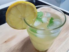 a lemonade drink with ice and mint garnish in a glass on a cutting board