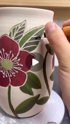 a person is painting a flower on a coffee cup