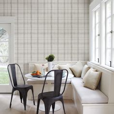 two chairs and a table in front of a window with a wall paper behind it