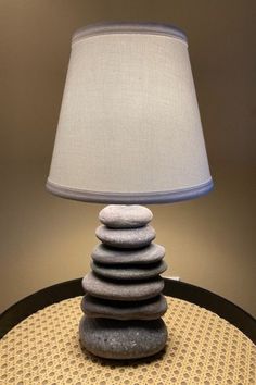 a lamp sitting on top of a table next to a stack of rocks with a blue shade