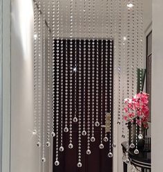 the door is decorated with crystal beads and pink flowers in vases on the table