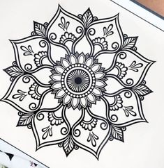 a drawing of a flower with black and white designs on the paper next to it