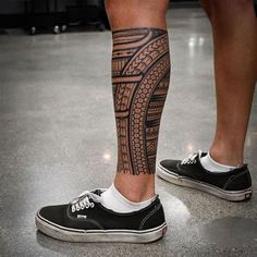 a man's leg with a tattoo on it and his shoes in the foreground