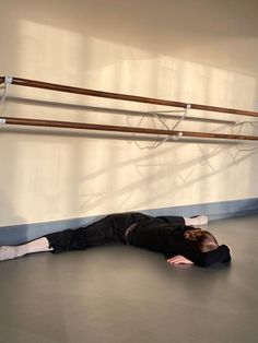 a woman laying on the floor in front of a wall with two wooden poles attached to it