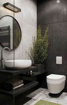 a bathroom with a toilet, sink and mirror next to a plant in the corner